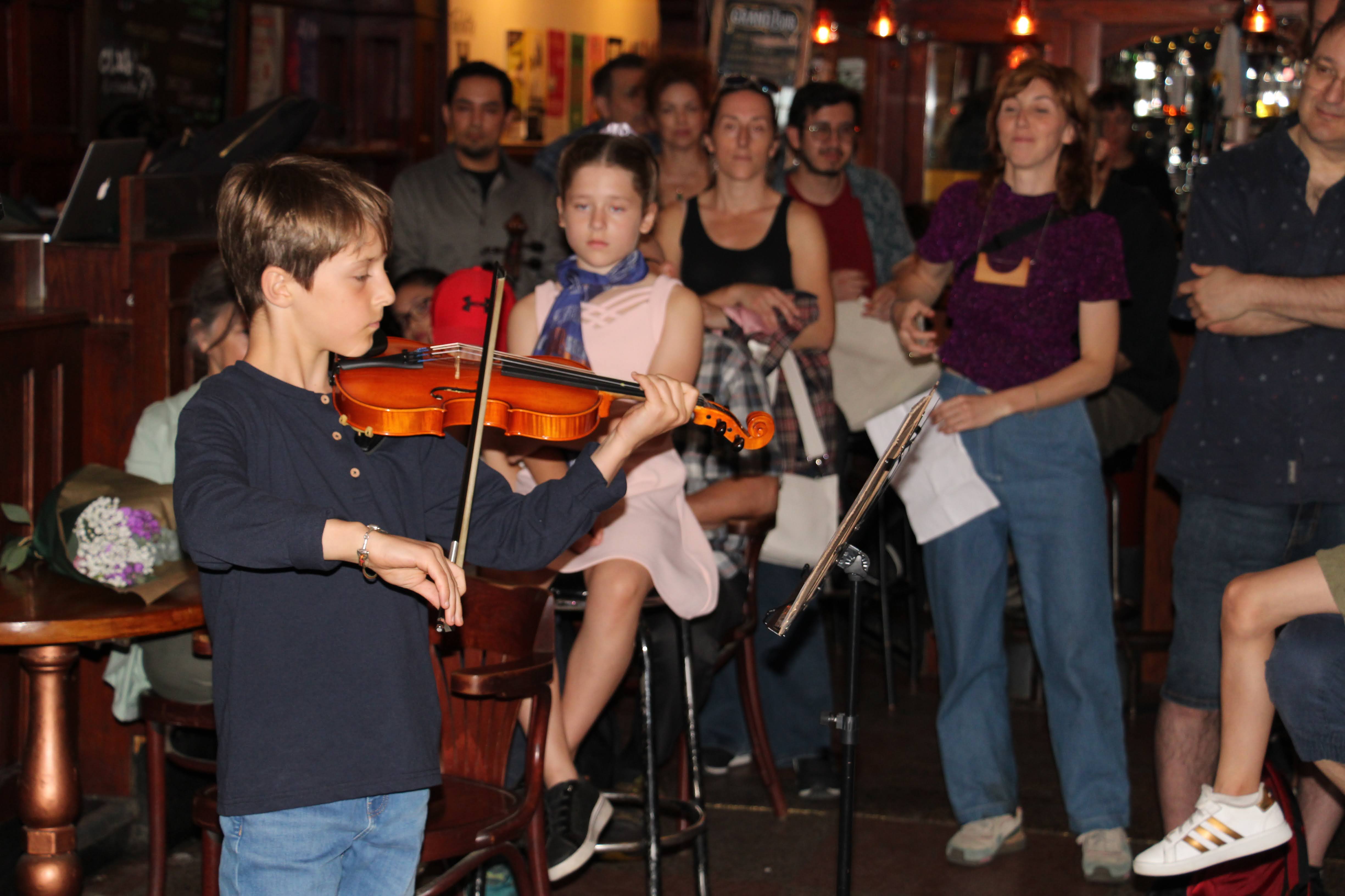 A young violin student performing in front of a receptive crowd at the Musiprof recital.